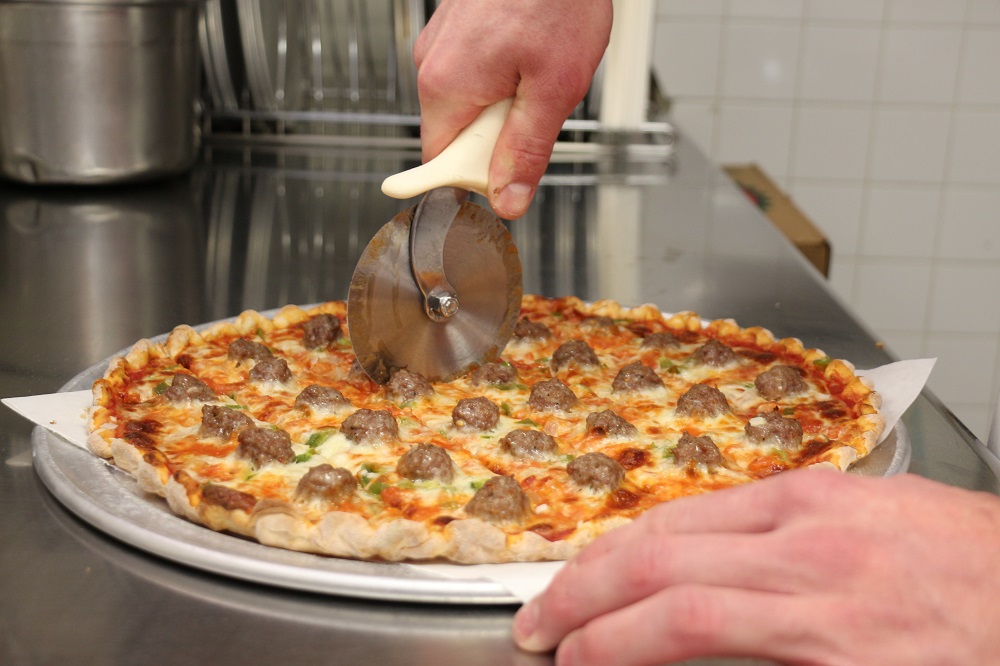 Cutting a sausage pizza